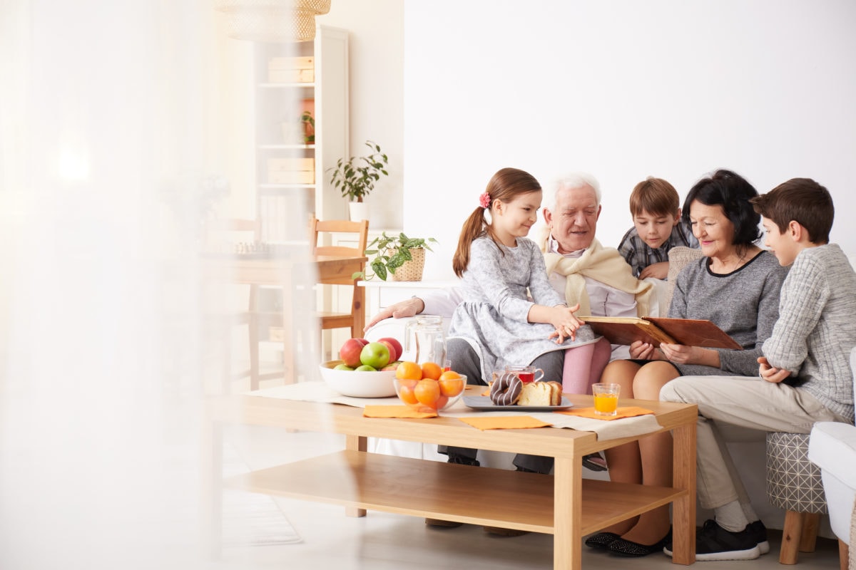 Happy grandparents showing photo album to their grandchildren in a living room